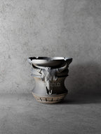 Vesseld.com 3D Printed Black Cylindrical Planter with skull design on a concrete background