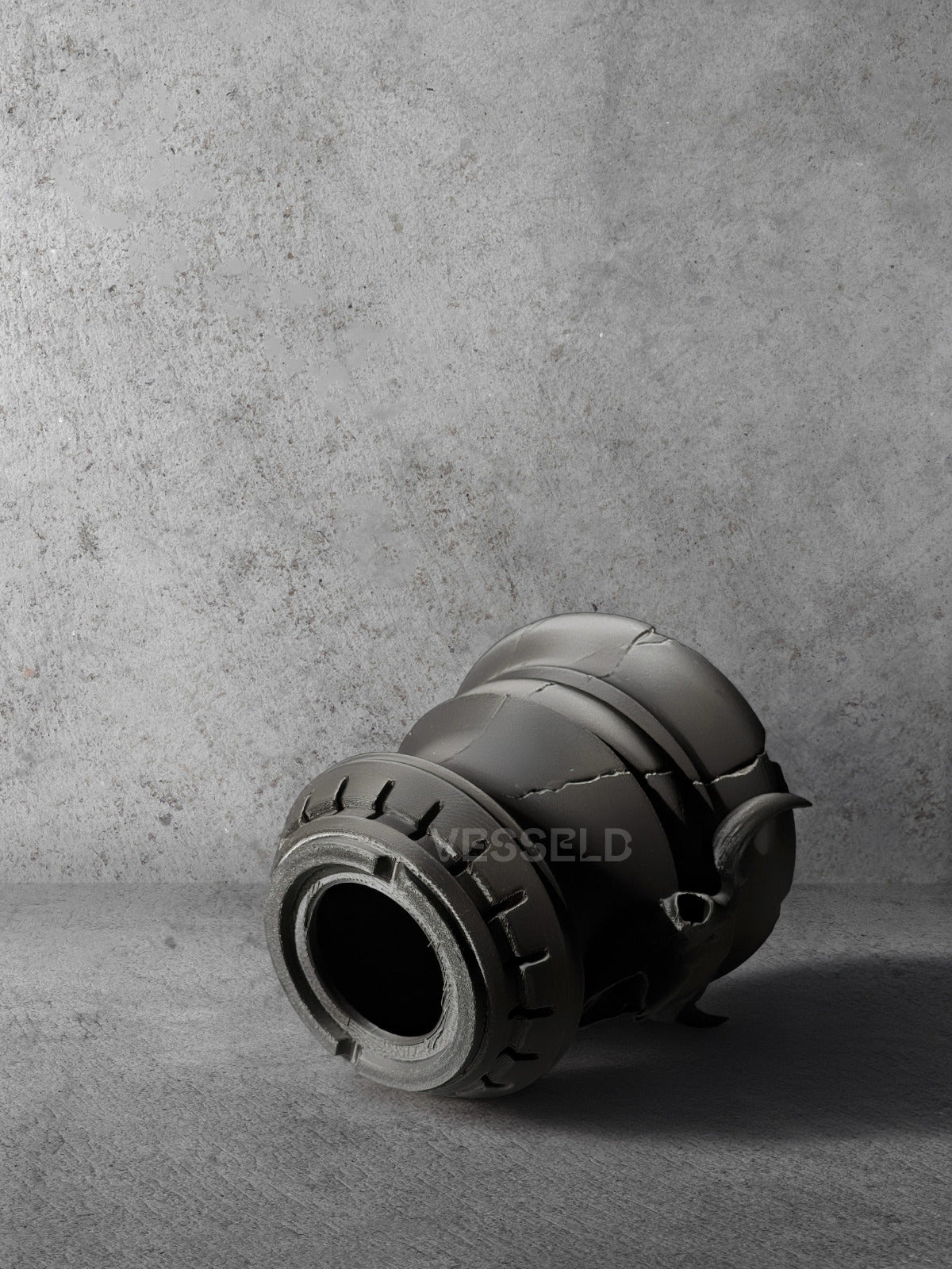 Vesseld.com Bottom of 3D Printed Black Cylindrical Planter with skull design on a concrete background