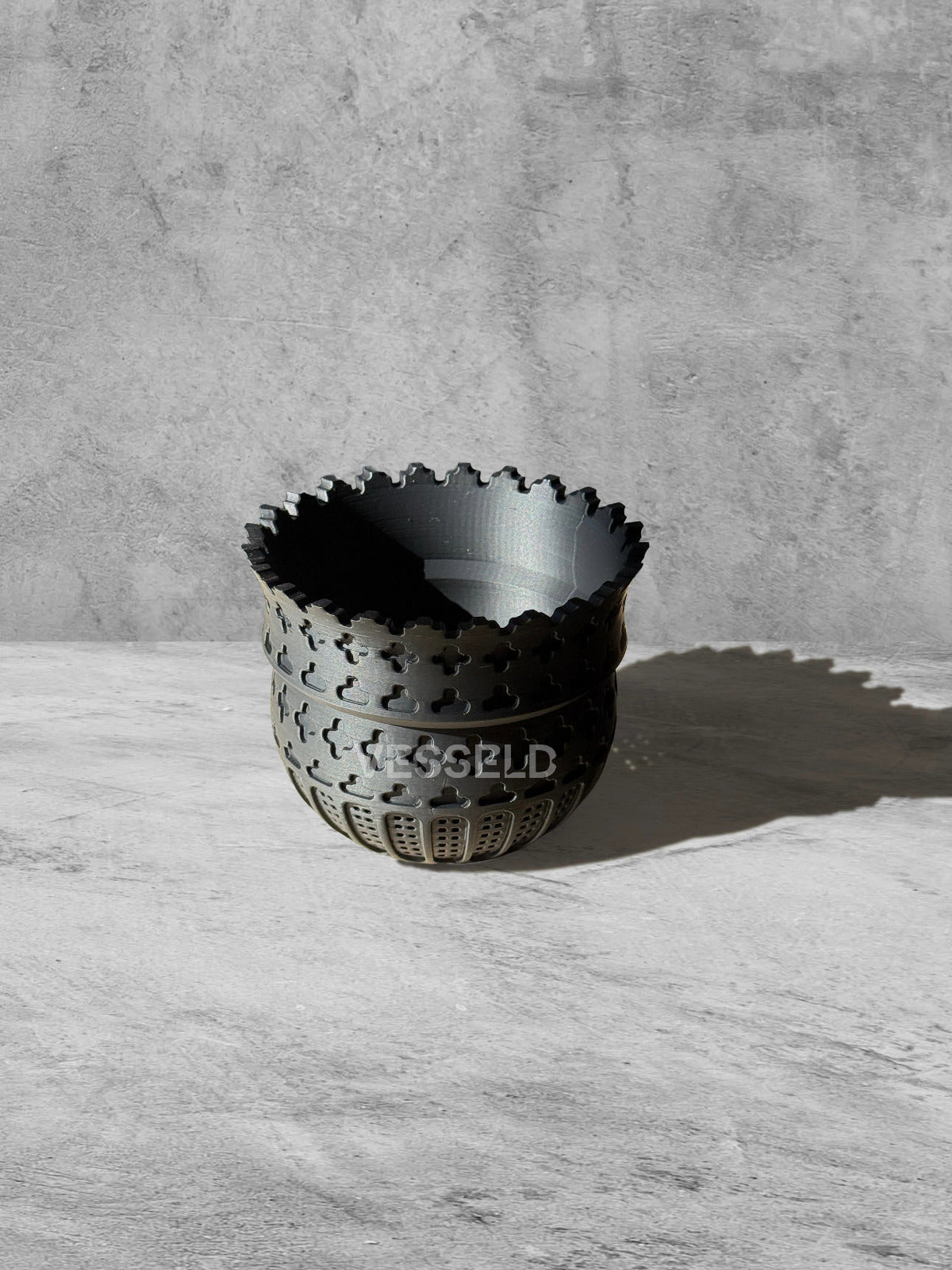 Vesseld.com Black textured bowl on a light gray surface with a concrete wall background